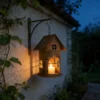 Rustic hanging house candle holder lantern glowing on a garden wall